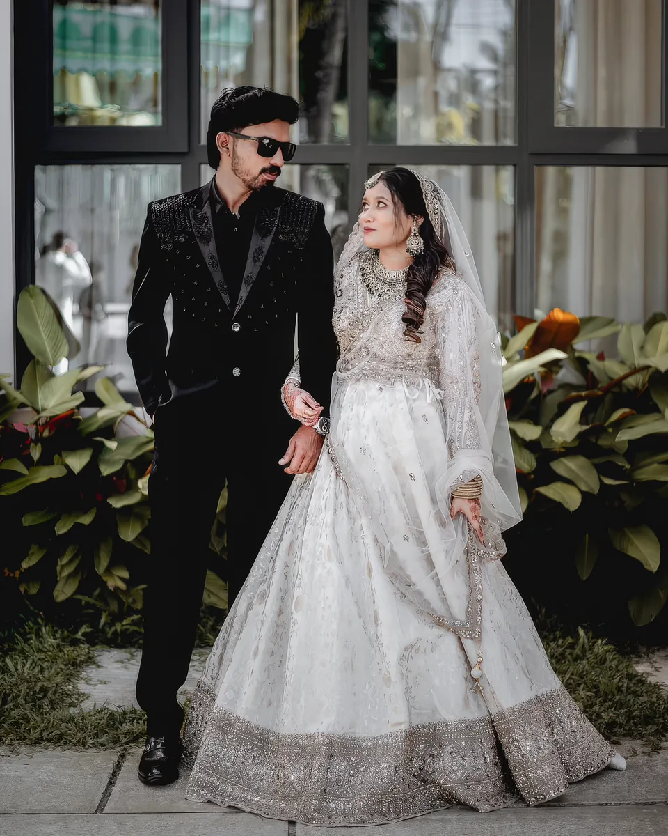 Mohamed Badusha and Mumthas Nadeera standing together in their wedding attire
